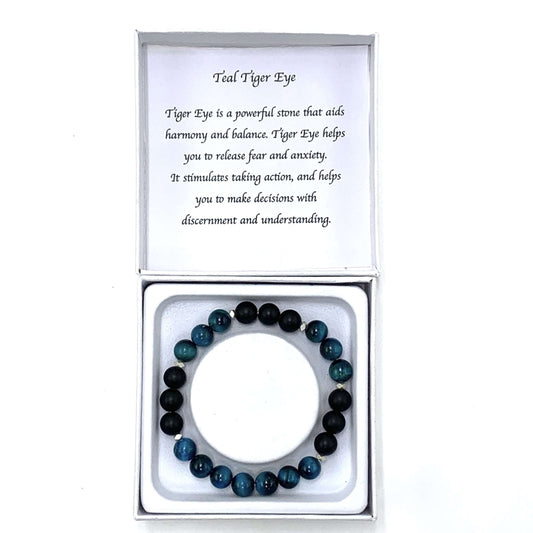 Teal and black beaded bracelet in a box with a card explaining the stone's properties.