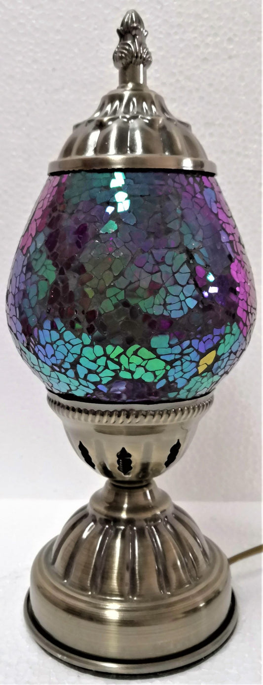A Turkish oval mosaic lamp with a reflective metal top and multicolored mosaic design body, on a metal base.
