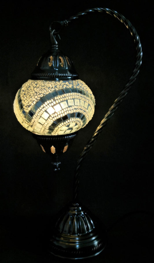 A Turkish mosaic lamp with a swan neck design featuring a white tiled base and a black metal stem, emitting a warm light.