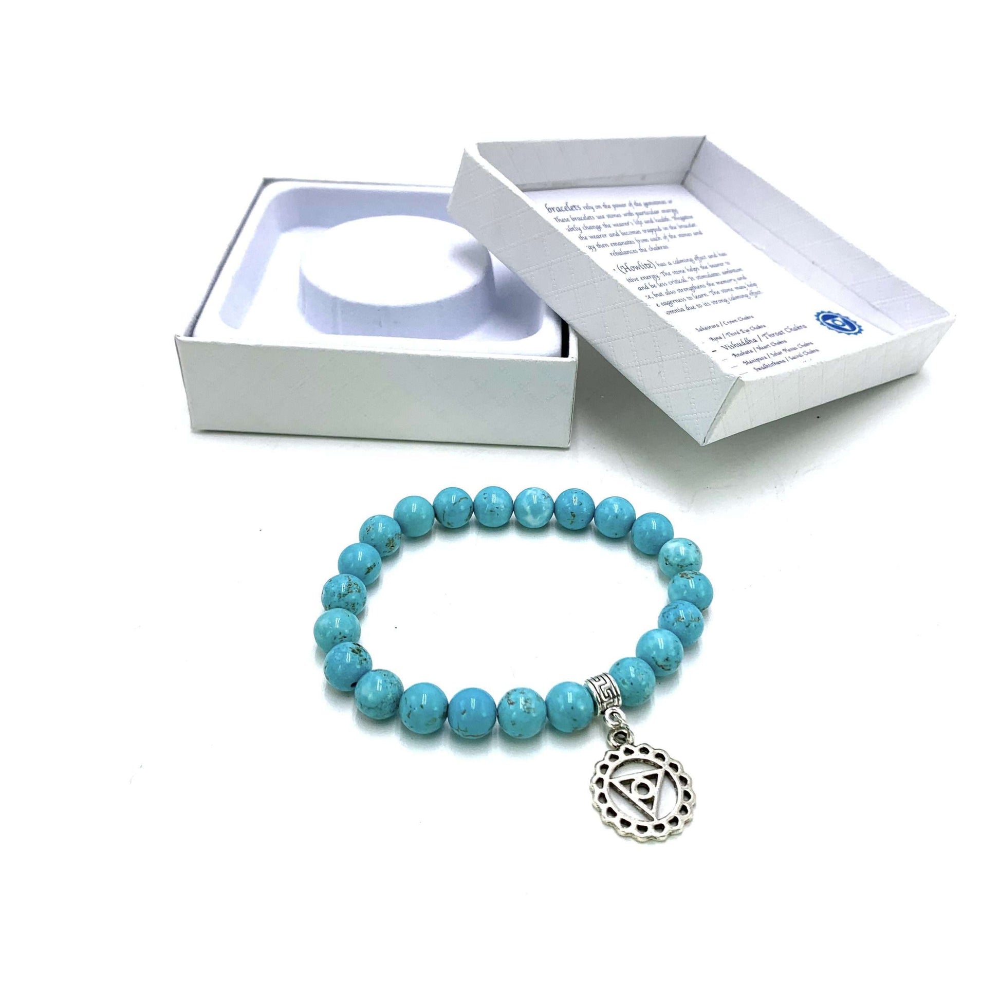 Turquoise beaded bracelet with a silver charm in front of a white box