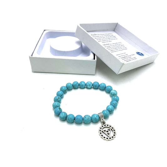 Turquoise beaded bracelet with a silver charm in front of a white box