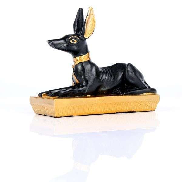 Statue of a black dog with gold accents on a white background