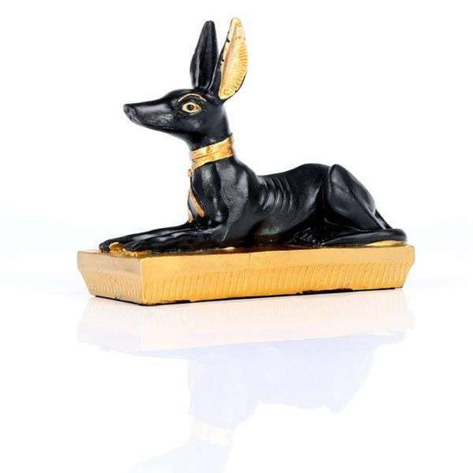 Statue of a black dog with gold accents on a white background