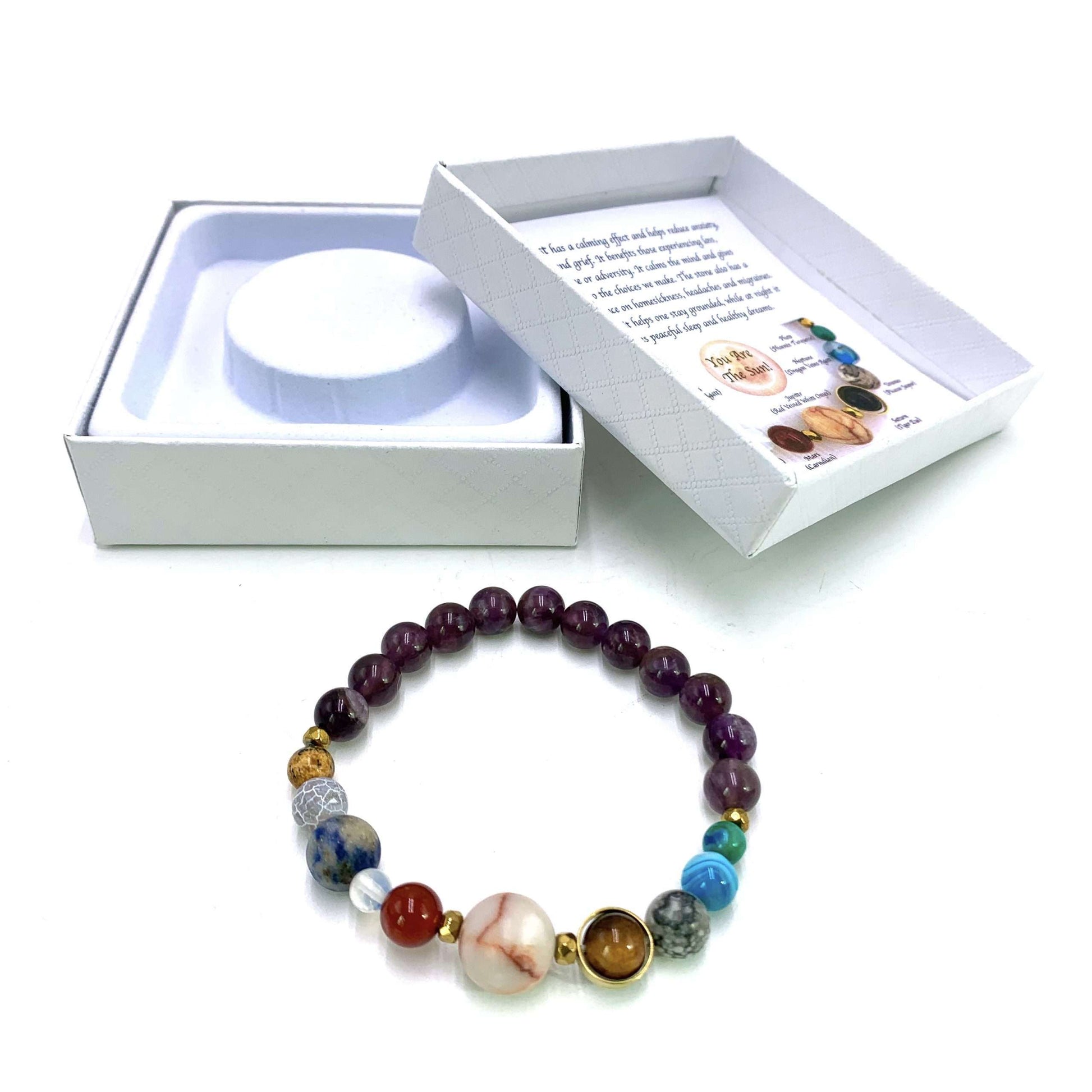 Colorful beaded bracelet with a white box containing a round object and a card on a white background
