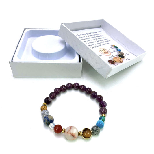 Colorful beaded bracelet with a white box containing a round object and a card on a white background