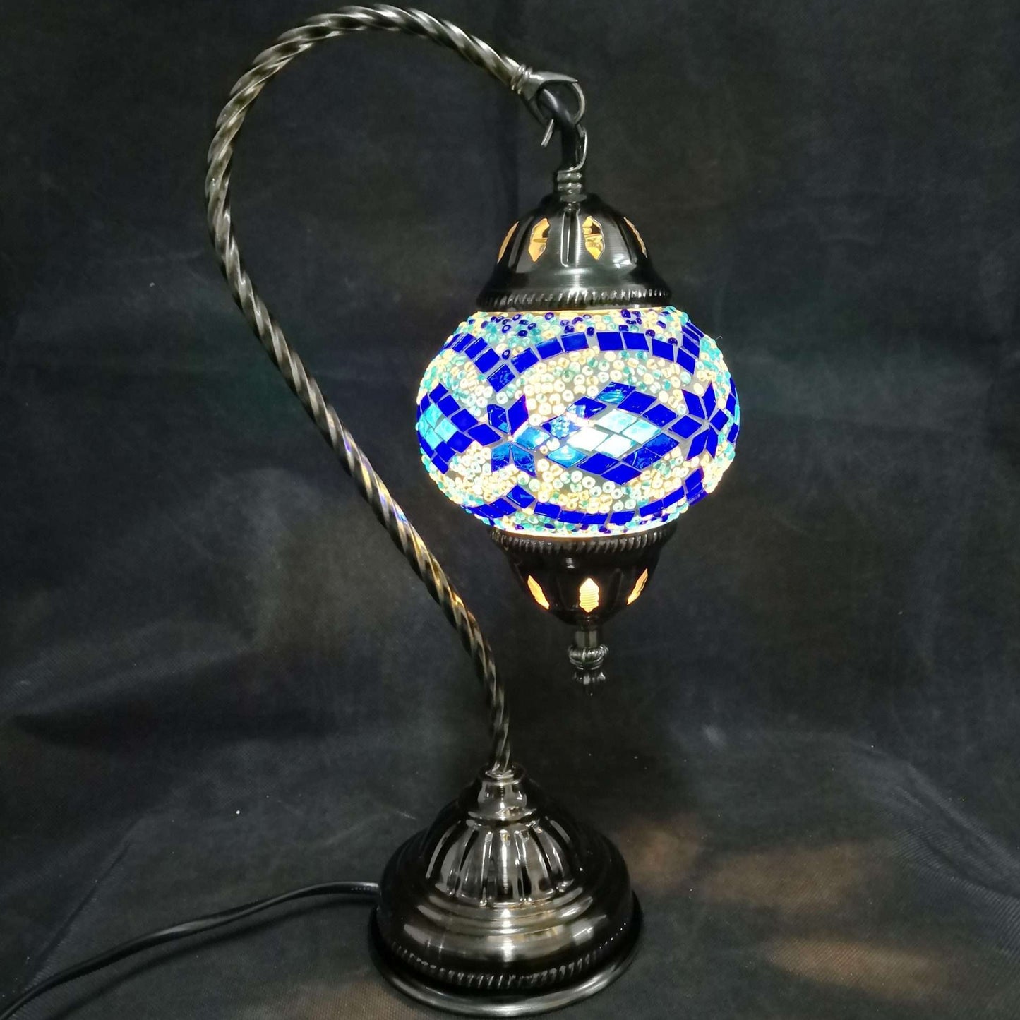 Decorative table lamp with a blue and white mosaic shade on a black background