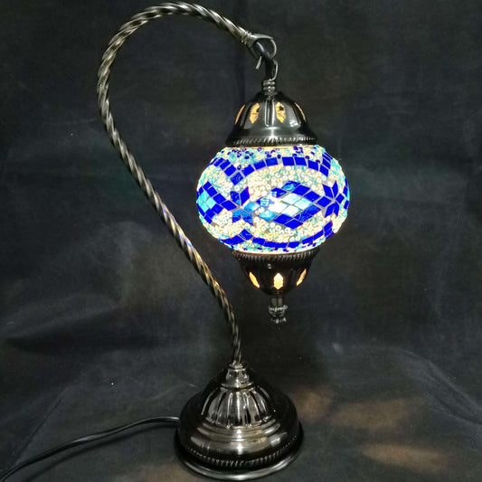 Decorative table lamp with a blue and white mosaic shade on a black background