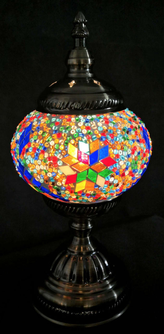 Colorful mosaic table lamp with a black base on a dark background