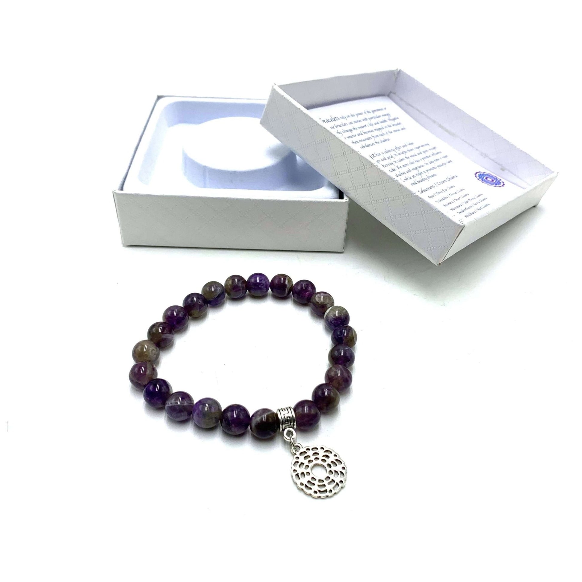 A purple amethyst crown chakra bracelet with a silver-colored fastener, displayed next to its open white box packaging.