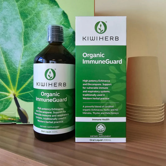 KiwiHerb Organic ImmuneGuard bottle and packaging on a wooden surface with green leaves in the background.