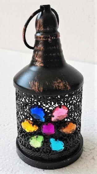 A black Moroccan lantern with colorful floral patterns in the design, used for holding candles.